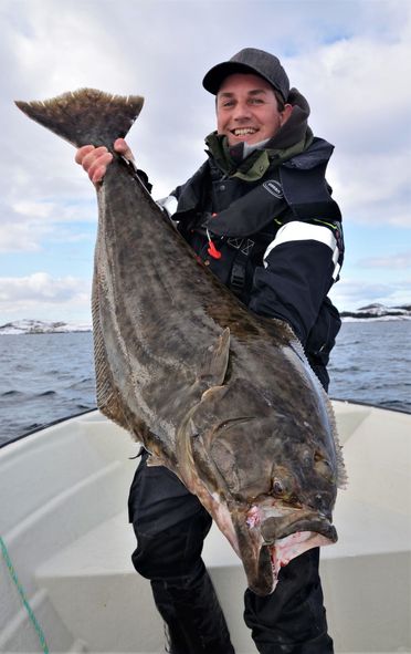 Mann holder stor fisk i båt