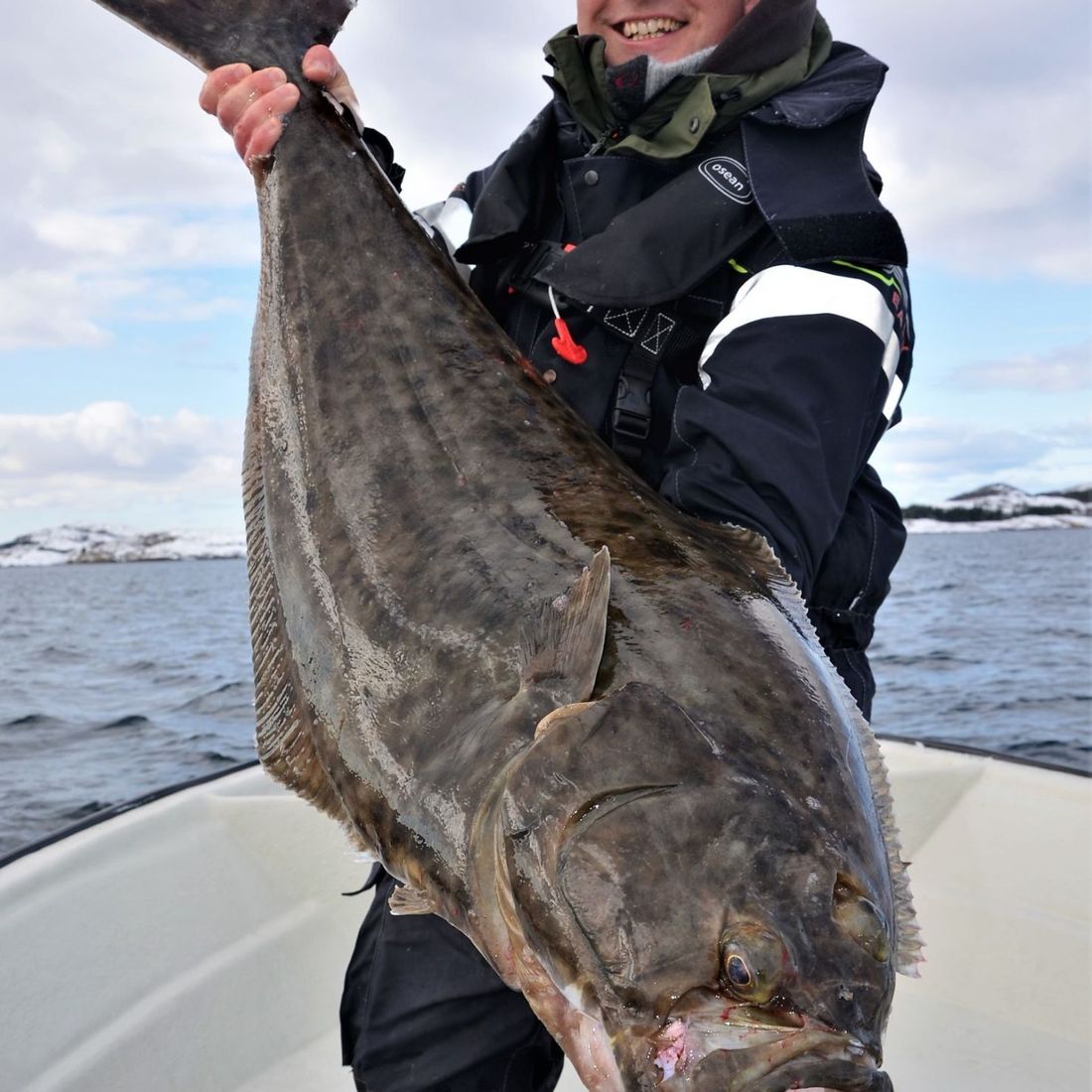 Mann holder stor fisk i båt