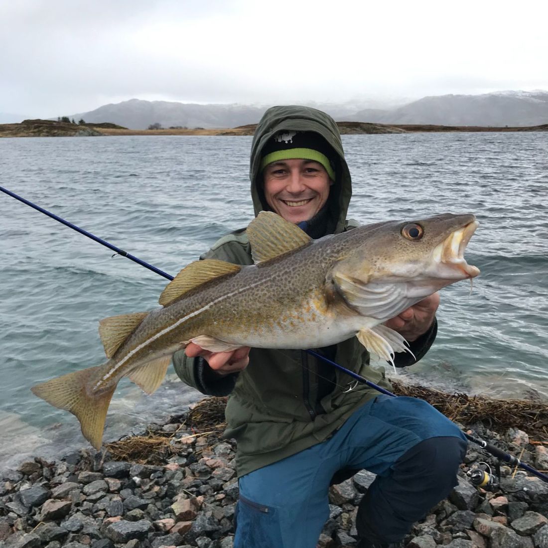Mann i fjære viser frem stor fisk