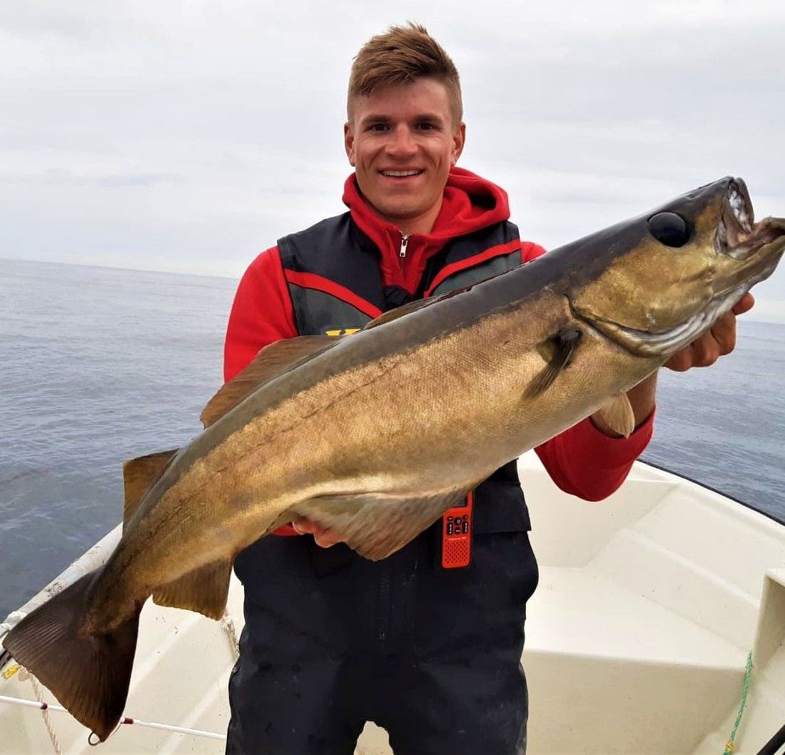 Mann i rød jakke holder frem fisk