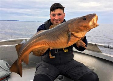 Mann i båt viser frem stor fisk